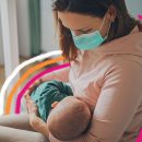 Uma mulher usando máscara amamenta seu bebê