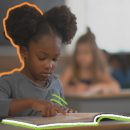 No chão da escola educação antirracista: Uma menina negra está na sala de aula e olha para seu caderno aberto em cima da carteira