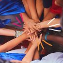 "Tudo bem ser diferente”: Foto de mãos de crianças, brancas e negras, com os braços estendidos no centro de um círculo