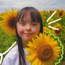 Foto de uma menina com síndrome de Down em meio a um campo de girassóis