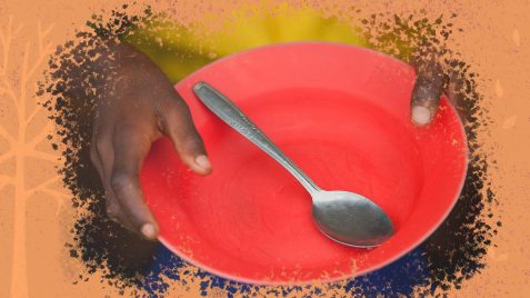 Foto de mãos negras segurando um prato vazio de cor vermelha