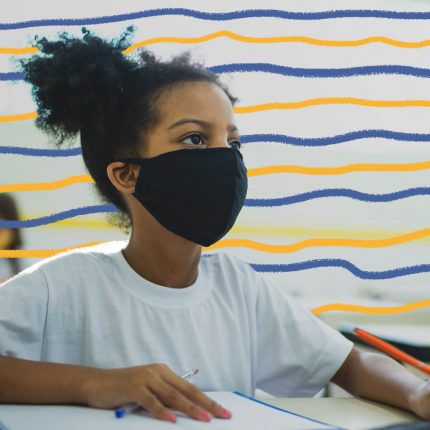 imagem de uma menina negra de cabelos crespos em uma sala de aula, sentada à frente da carteira, usando máscara de proteção contra covid