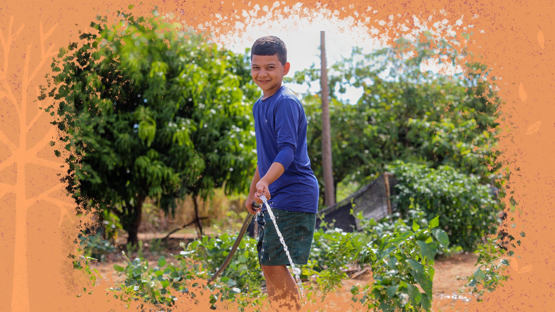 Um menino, vestido de shorts e camisa azul, está regando uma plantação com uma mangueira, e sorrindo para a foto. Ele está em um cenário de crise hídrica