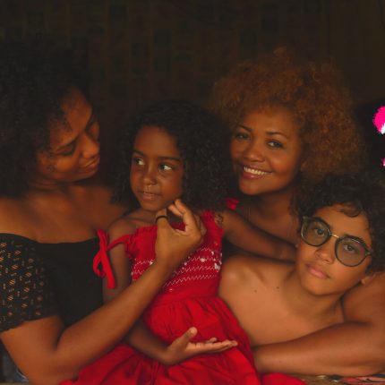 Foto em que Gaby Amarantos aparece ao lado do filho Davi; da irmã, Gabriele; e da sobrinha, Ana Vitória. Os quatro estão apoiados em uma janela de madeira pintada em partes de laranja.