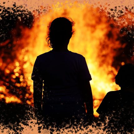 Silhueta de duas crianças, de costas, de mãos dadas, olhando para um incêndio