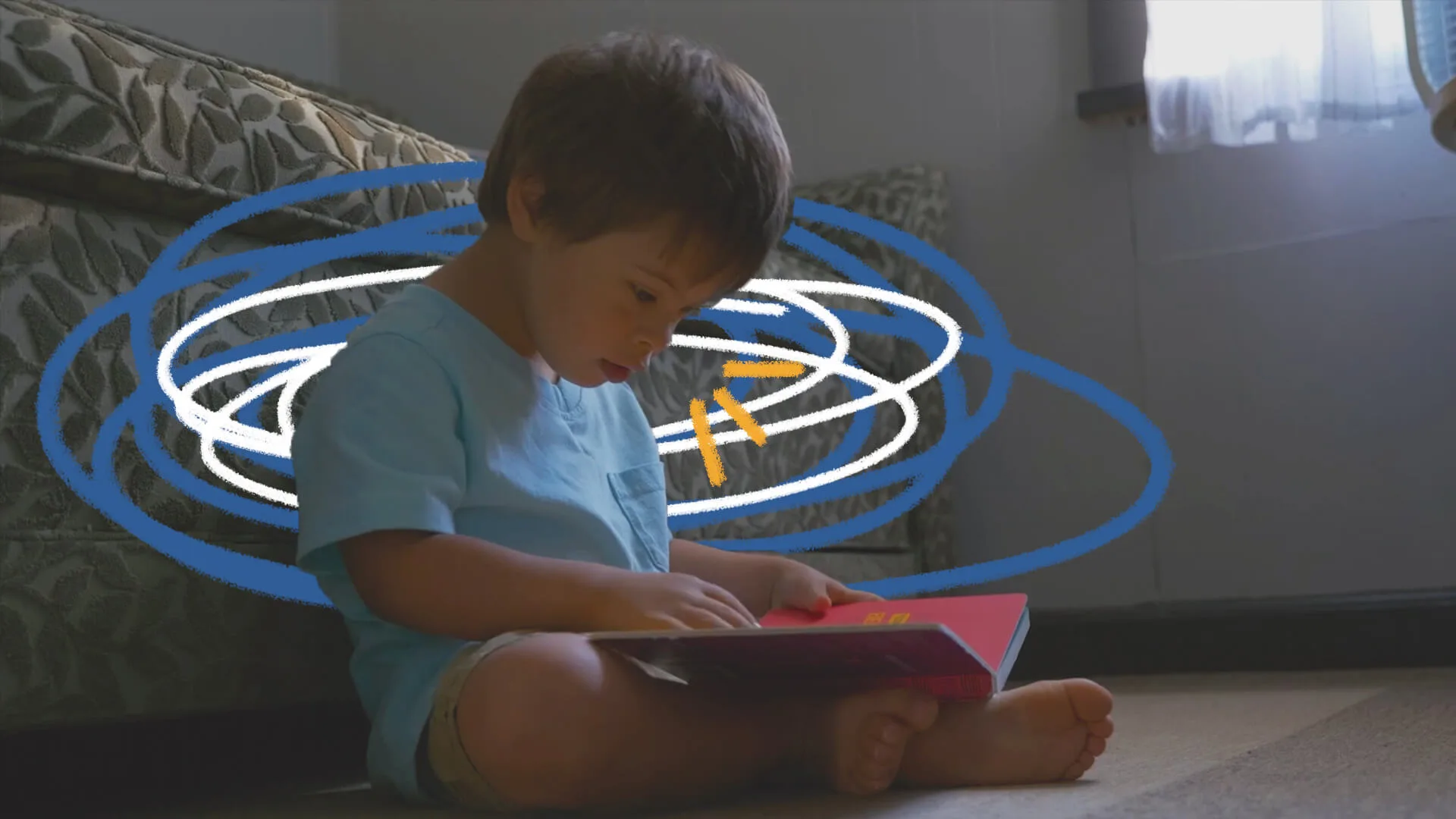 Cena do filme "Um lugar para todo mundo" em que Emílio, um menino que tem síndrome de Down, está sentado no chão, encostado no sofá, com um livro vermelho aberto no colo. Ele veste uma camiseta azul.