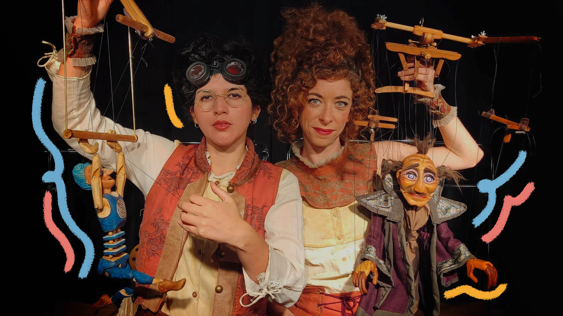 Na foto, atrizes do espetáculo Gabinete de Curiosidades olham para frente enquanto seguram marionetes. Ambas têm pele clara e usam vestimentas nas cores laranja, branco e vermelho.