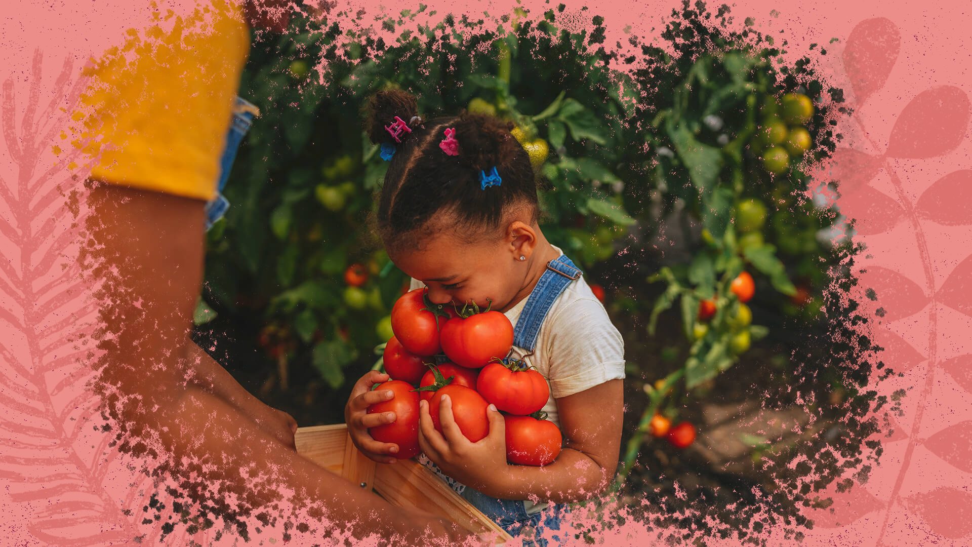Na foto, uma menina negra sorri enquanto segura vários tomates. A imagem contém uma intervenção de moldura na cor rosa.