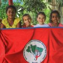 Na foto, crianças seguram uma bandeira do Movimento dos Trabalhadores Rurais Sem Terra (MST).