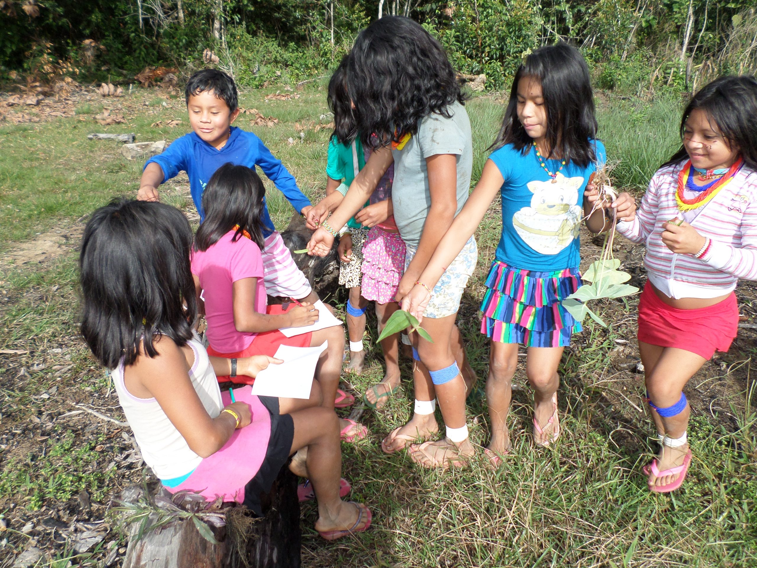 Crianças indígenas estão reunidas escrevendo em cadernos e interagindo