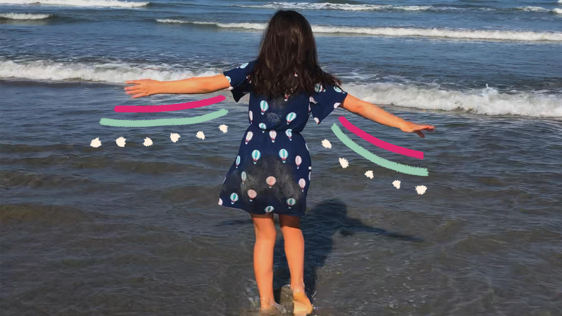 Na foto, uma menina com vestido azul olha para o mar com os braços abertos. A imagem possui intervenções coloridas.