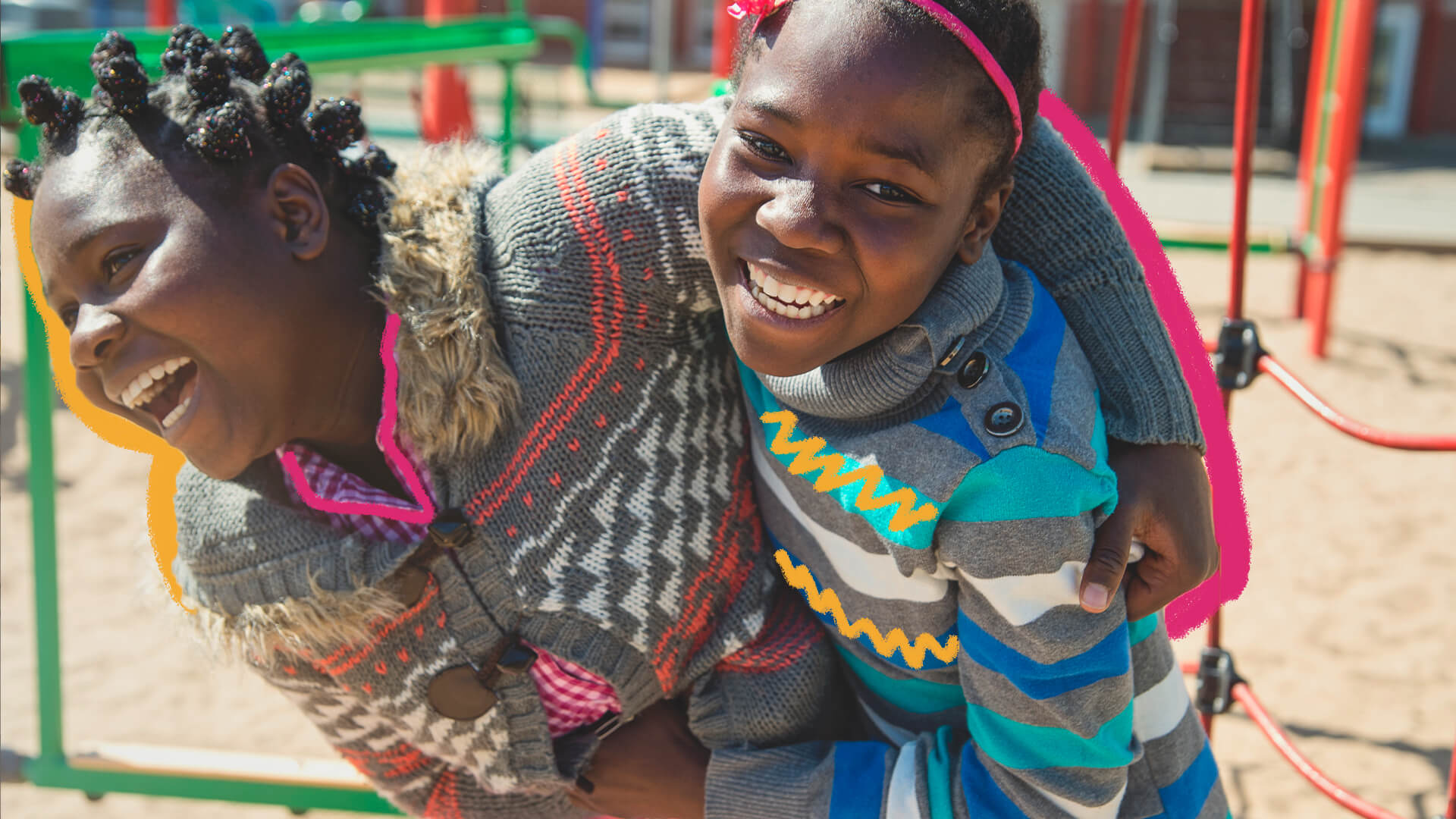 As brincadeiras africanas de Weza: na foto, duas meninas negras brincam em um parquinho. Elas sorriem e usam suéteres coloridos com fundo cinza.