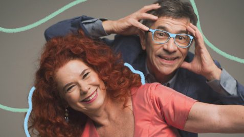 Na foto, Sandra Peres e Paulo Tatit, músicos da dupla Palavra Cantada. Eles têm pele clara e aparecem sorridentes. A foto possui intervenções de rabiscos coloridos.