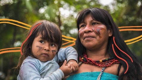 Na imagem, uma mulher e uma menina indígena. Atrás delas, árvores desfocadas. A imagem possui intervenções de rabiscos coloridos.