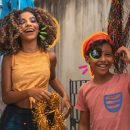 5 passos para fazer um carnaval em casa com as crianças: na imagem, duas crianças seguram confetes e adornos para fantasias de carnaval.