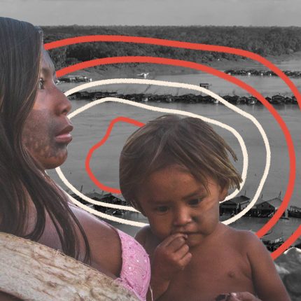 Foto de uma mulher indígena segurando um menino no colo às margens de um rio