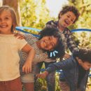 Cultura da infância: Um grupo de quatro crianças, duas meninas e dois meninos, estão brincando ao ar livre