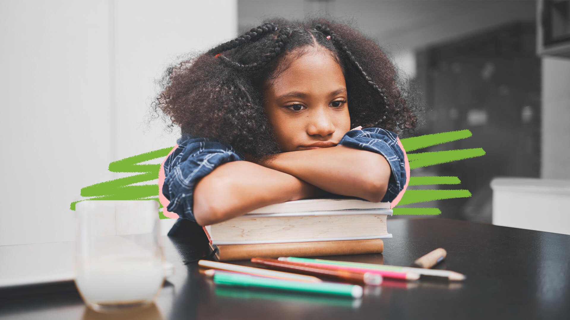 Na foto, uma menina negra, com tranças no cabelo, está de braços cruzados em cima de dois livros fechados. Há lápis coloridos espalhados pela mesa.