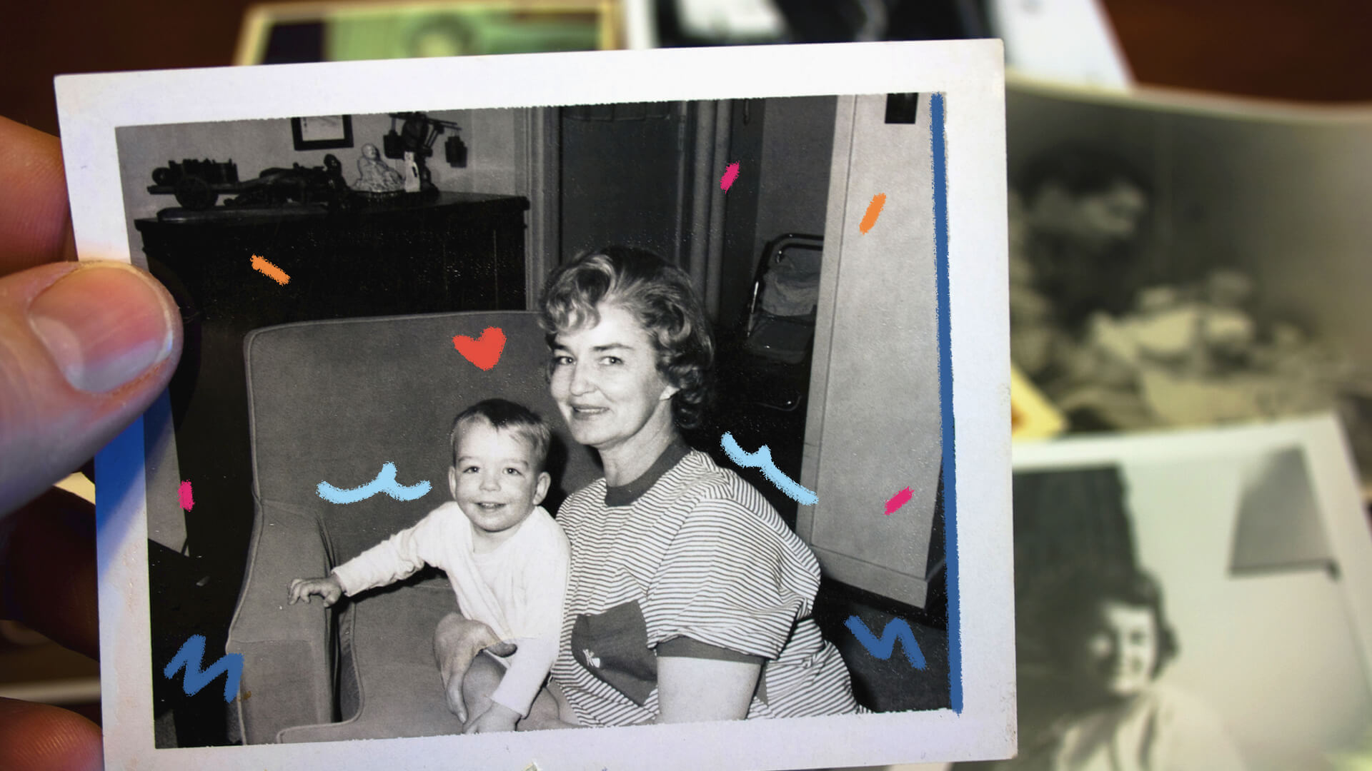 Na imagem, fotografia polaroid de uma mãe com o filho. Eles são brancos, sorriem e estão em uma poltrona. A imagem possui intervenções de rabiscos coloridos.