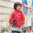 Foto de uma menina de origem asiática vestindo um casaco vermelho na rua que participou da série "Crescidinhos"