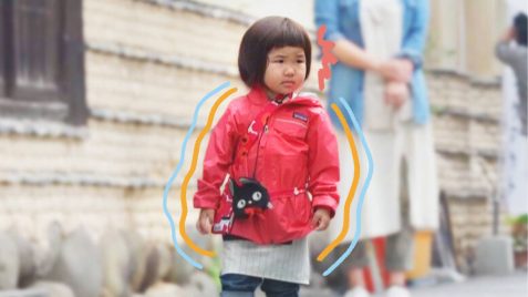 Foto de uma menina de origem asiática vestindo um casaco vermelho na rua que participou da série "Crescidinhos"