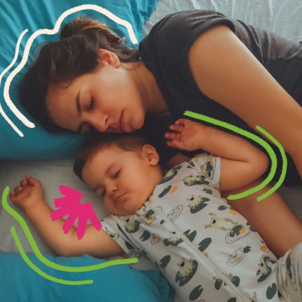 Uma mulher adulta e um bebê estão lado a lado na hora de dormir. A roupa de cama é em tons de azul