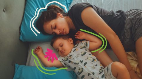 Uma mulher adulta e um bebê estão lado a lado na hora de dormir. A roupa de cama é em tons de azul