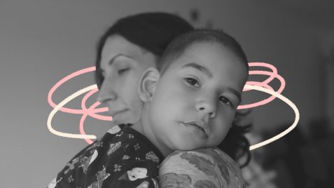 Na foto, uma mãe segura o filho no colo, que apoia a cabeça em seu ombro. A imagem está em preto e branco e possui intervenções de rabiscos coloridos.