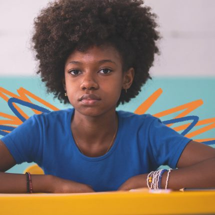 Fechamento das escolas: na imagem, uma menina negra de camiseta azul olha para frente com um semblante sério. A imagem possui intervenções de rabiscos coloridos.