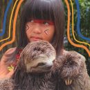 Uma menina indígena segura um bicho-preguiça que é seu xerimbabo