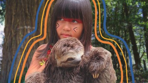 Uma menina indígena segura um bicho-preguiça que é seu xerimbabo
