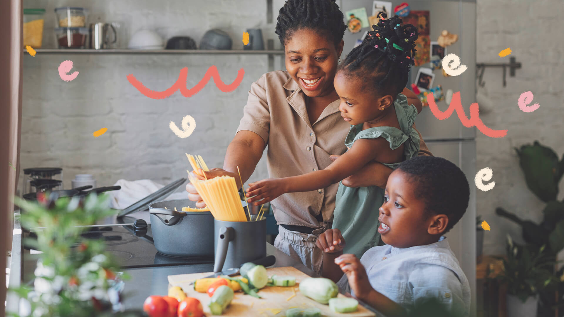 Foto de uma mulher cozinha em uma cozinha com um menino e uma menina. Ela mostra um livro de receitas para a menina enquanto o menino está em frente a uma tábua com vários legumes cortados