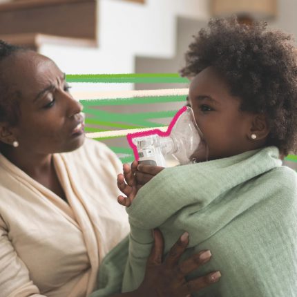 Na foto, uma mulher negra está ajudando uma criança negra, enrolada em uma pano, a respirar com um inalador.