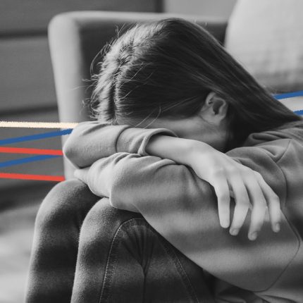 Uma menina está sentada e esconde o rosto nos braços, apoiados nos joelhos. A imagem está em preto e branco e possui rabiscos coloridos.