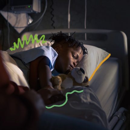 Um menino negro está dormindo em uma cama de enfermaria.