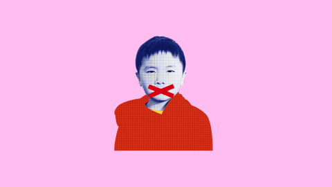Foto de uma criança asiática com um "x" nos lábios. O fundo é rosa e o menino veste vermelho.