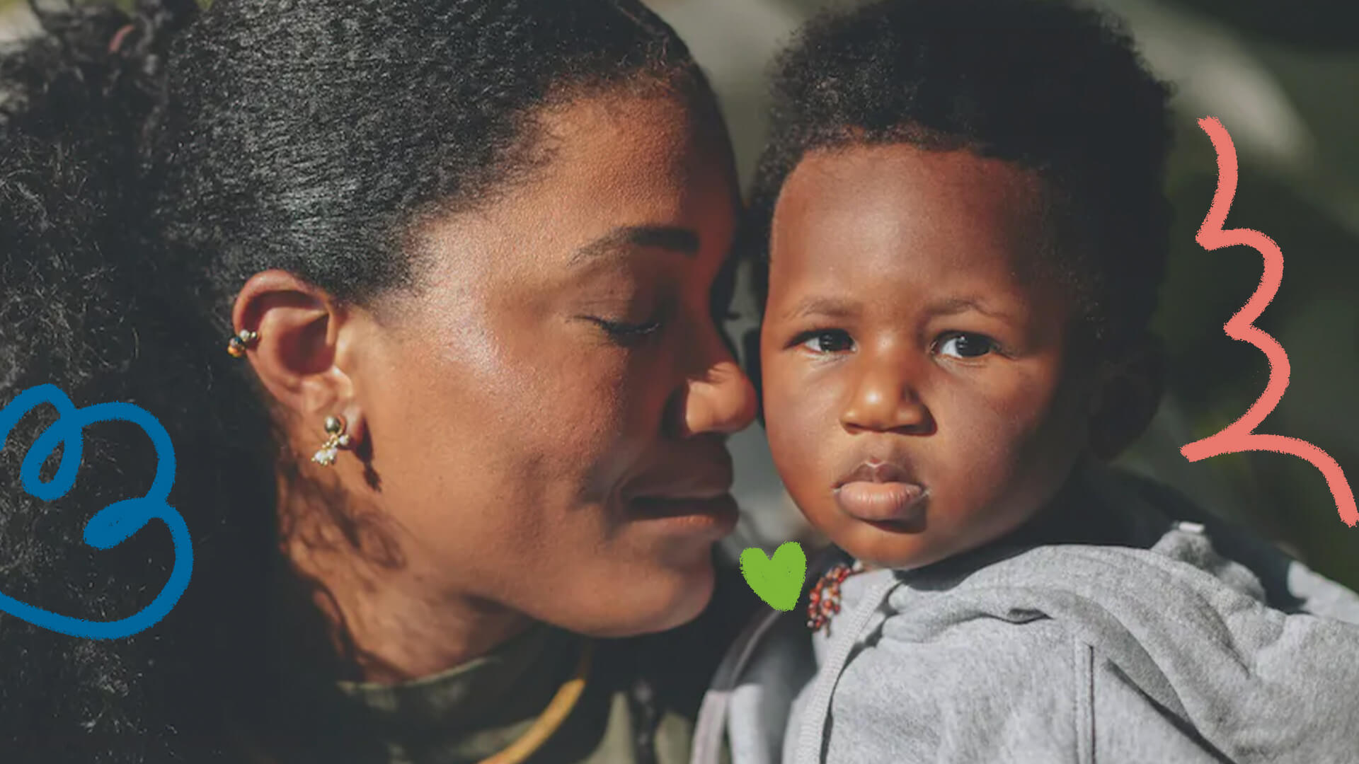 Imagem de uma mulher negra encostando o nariz em seu filho, um menino negro de dois anos. A mulher é Luedji Luna, possui pele escura e cabelos crespos pretos; seu filho, Dayo, também possui pele escura e veste um moletom cinza.
