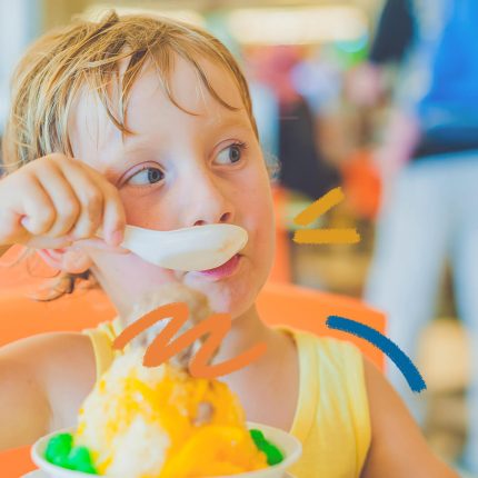 Creme de manga: foto de um menino loiro, branco e de olhos azuis que come uma sobremesa de creme de manga com uma colher.