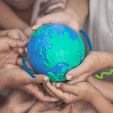 Foto colorida de mãos de crianças que seguram uma maquete do planeta Terra