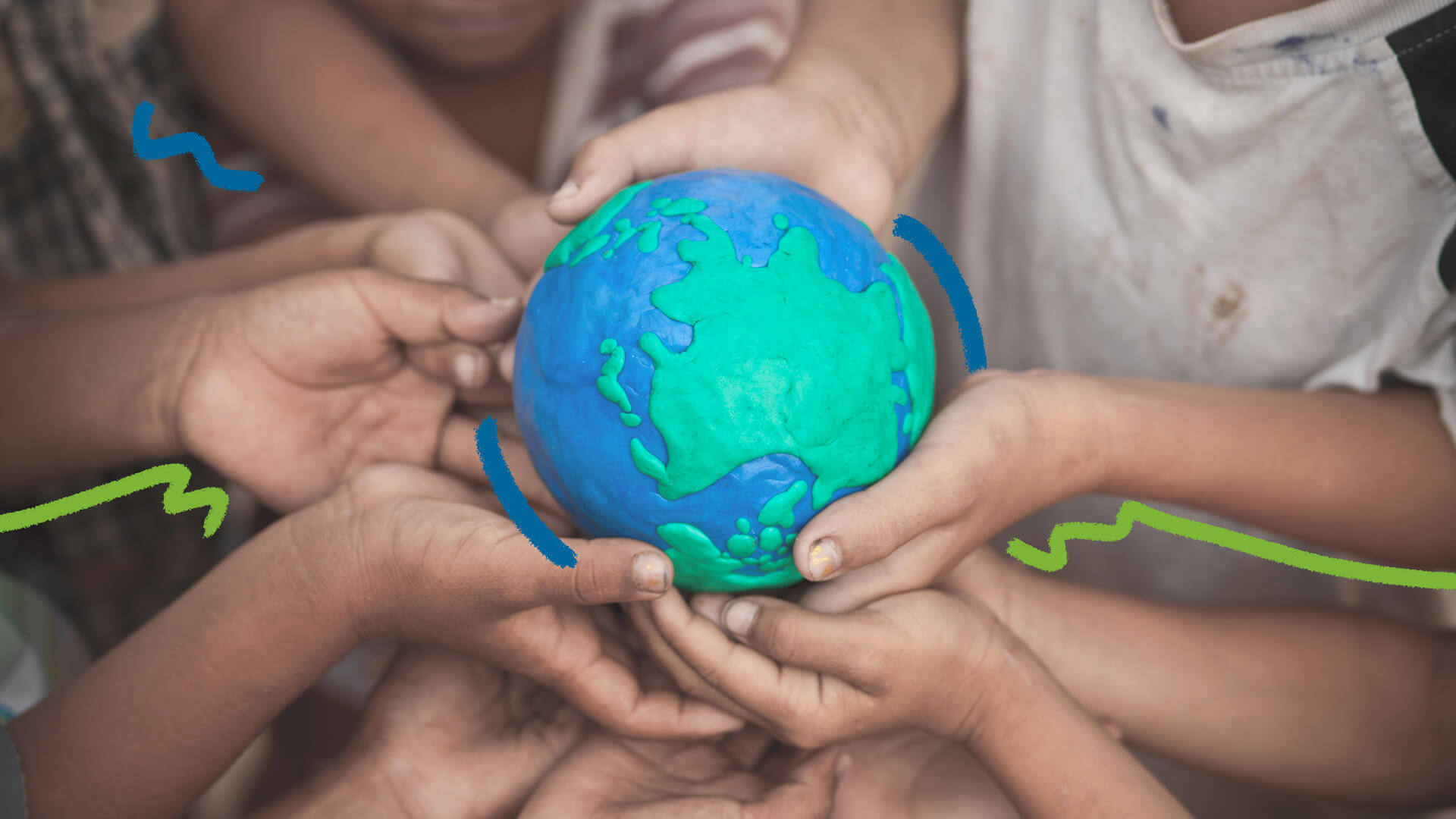 Foto colorida de mãos de crianças que seguram uma maquete do planeta Terra