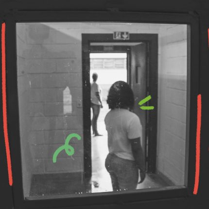 Foto em preto e branco de duas jovens de costas separadas por uma porta