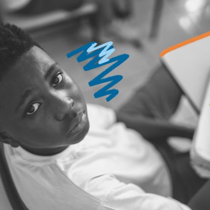 Xenofobia: foto em preto e branco de um menino sentado numa carteira em sala de aula.
