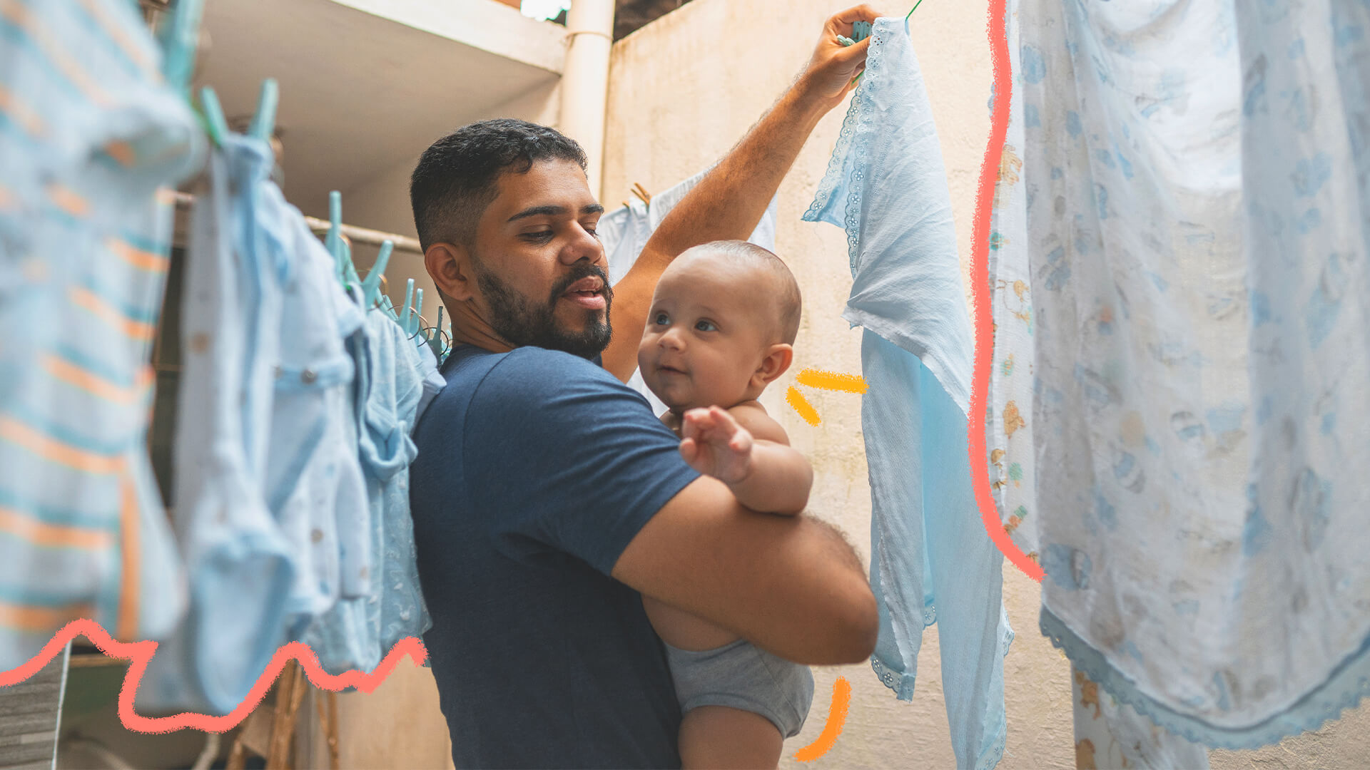 Foto de um homem com um bebê no colo enquanto estende fraldas no varal