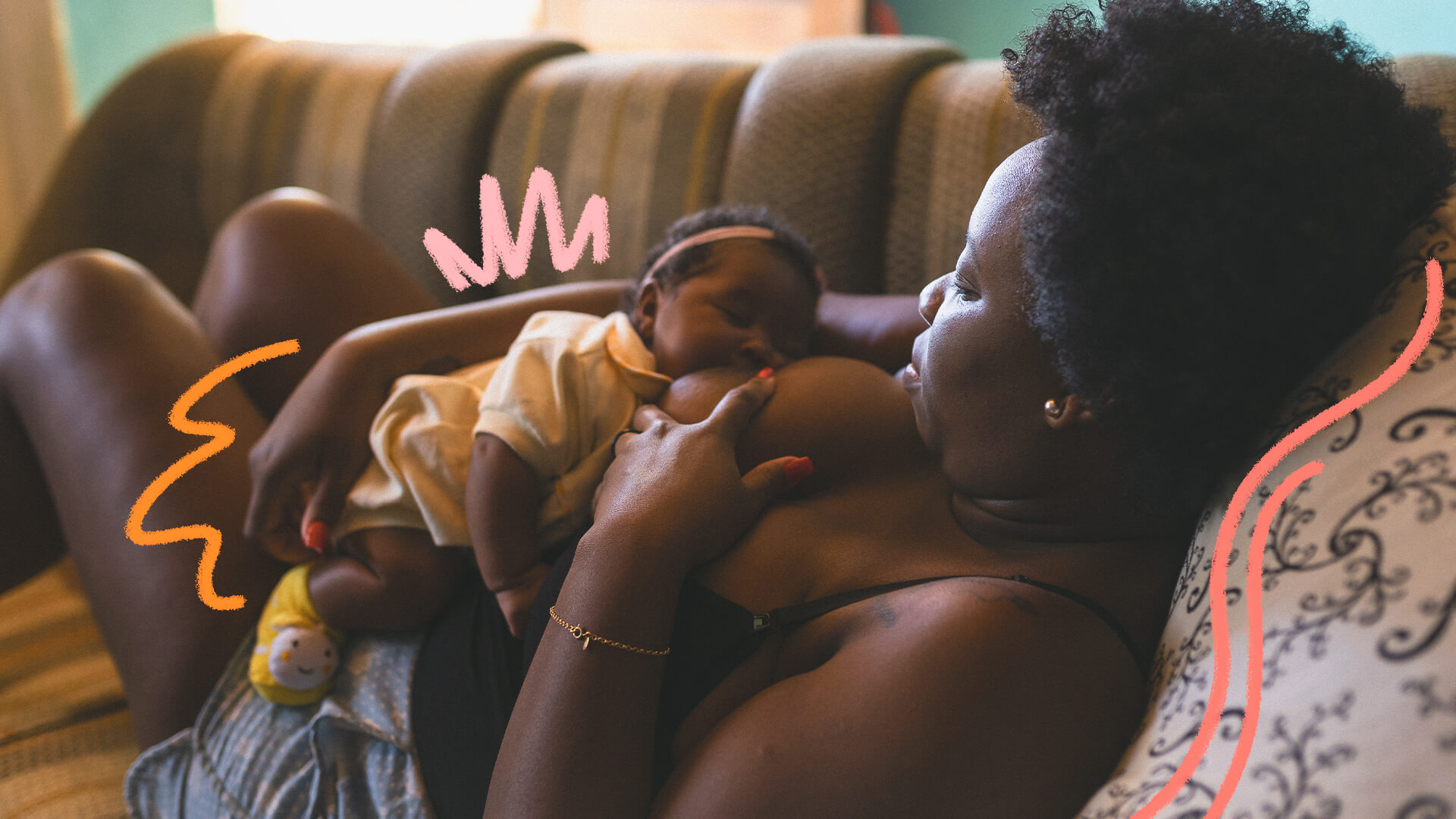 Foto de uma mulher amamentando sua bebê enquanto está deitada no sofá. Ambas são negras