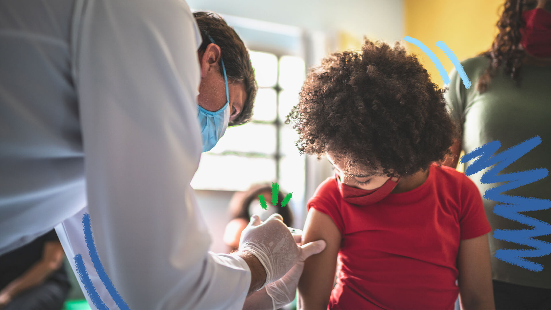 Um profissional da saúde de jaleco branco e máscara azul aplica uma vacina no braço de um menino que usa máscara e camiseta vermelha