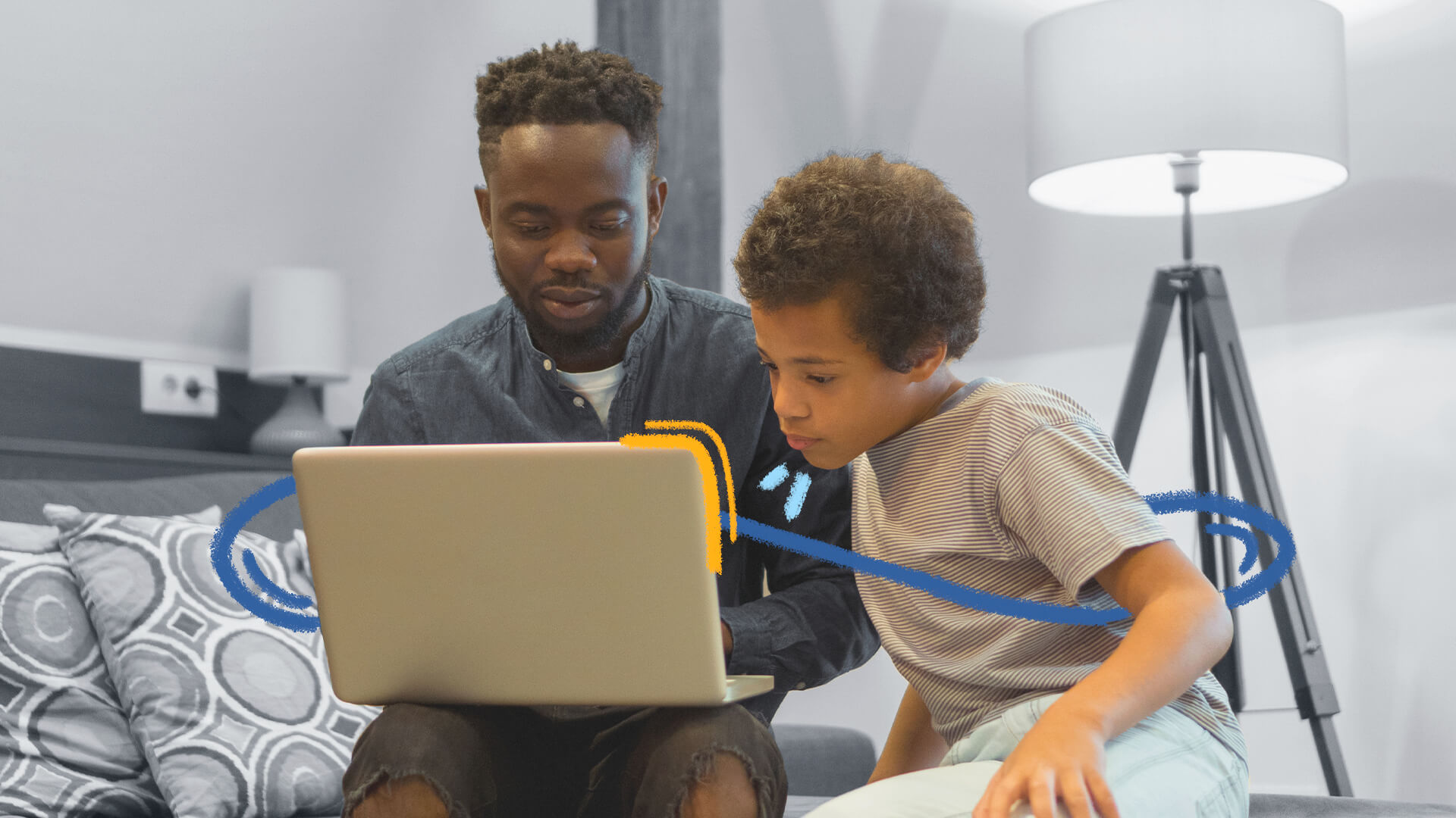 Foto de um adulto e um menino, ambos negros, sentados em frente a um computador