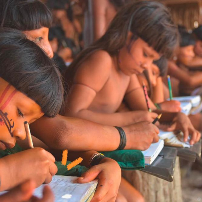 Foto de um grupo de crianças indígenas escrevendo em seus cadernos