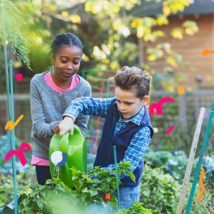 Na imagem, duas crianças regam um jardim.