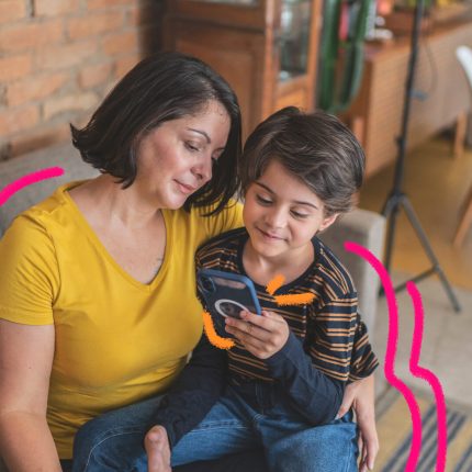 Uma mãe e um filho utilizam um celular juntos. A imagem ilustra a matéria 96% das crianças acessam a internet todos os dias, diz pesquisa TIC Kids Online