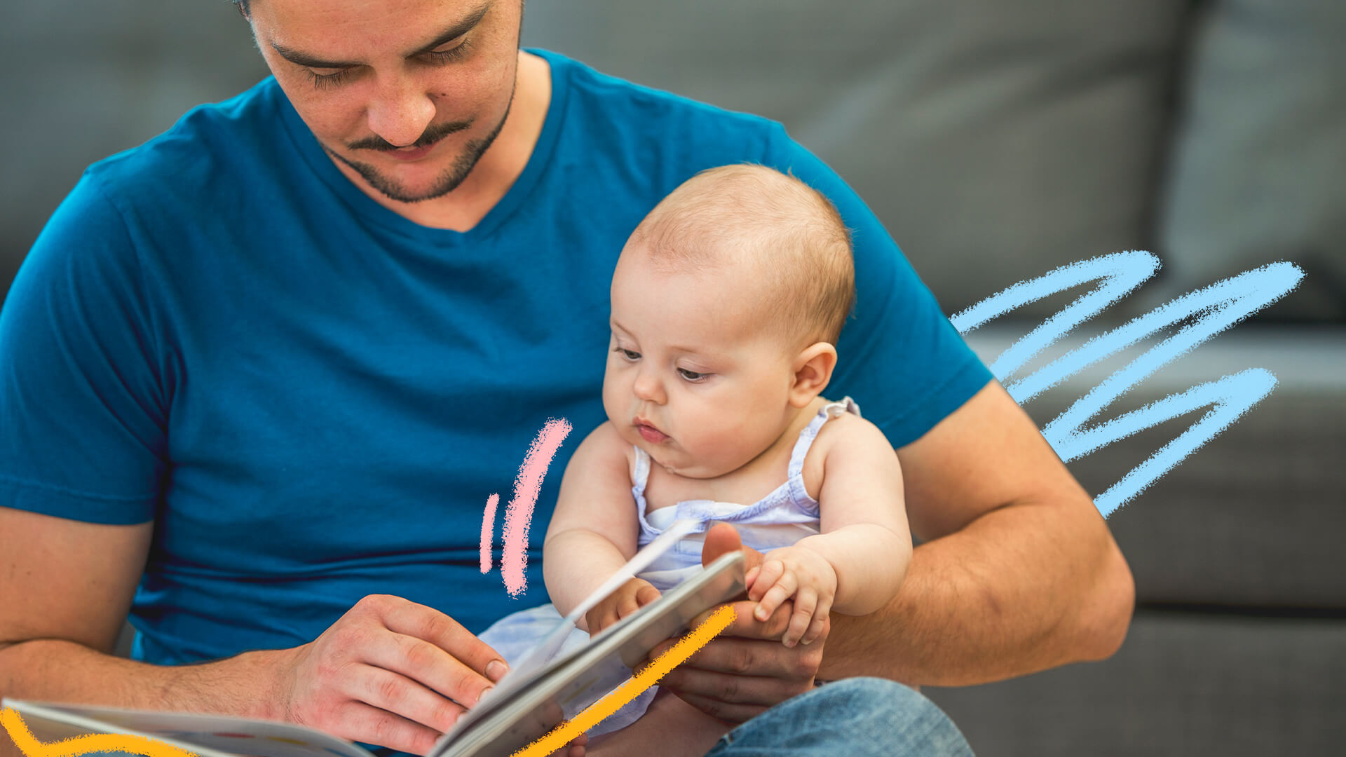Foto de um bebê que lê um livro junto do pai. O homem usa camiseta azul.